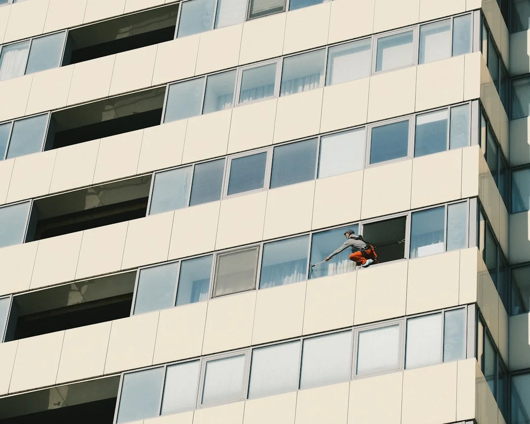 services-02 During daylight hours, three window washers hanging from ropes meticulously clean the glass exterior of a contemporary building.